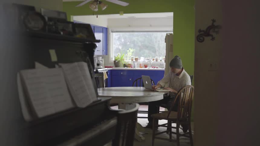 Man Working On Computer At Kitchen Table