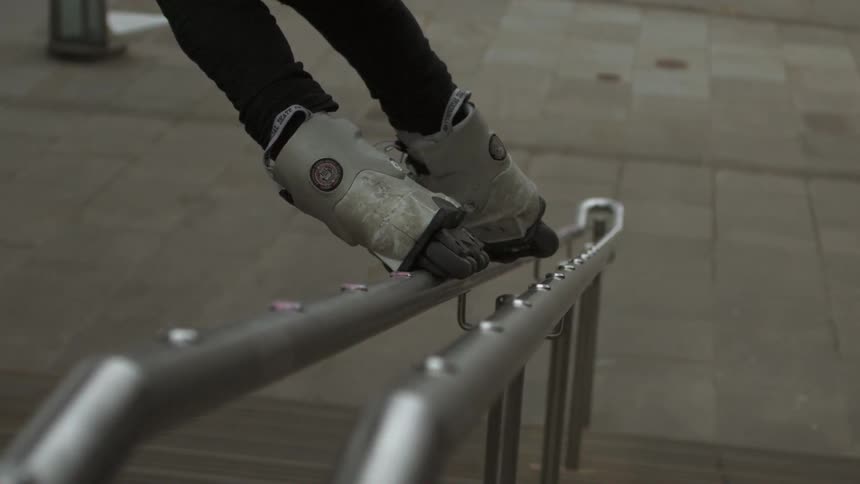 Person sliding down a handrail wearing rollerblades