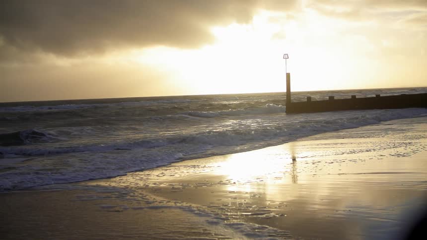 View of the water crashing on a beach as the sun sets