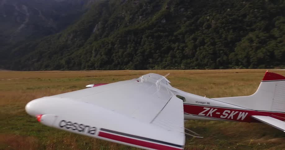 A large red and white plane is running as it stands on a grass field