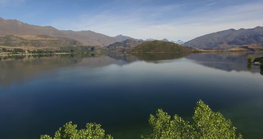 A still lake reflects a cloudless sky and mountains