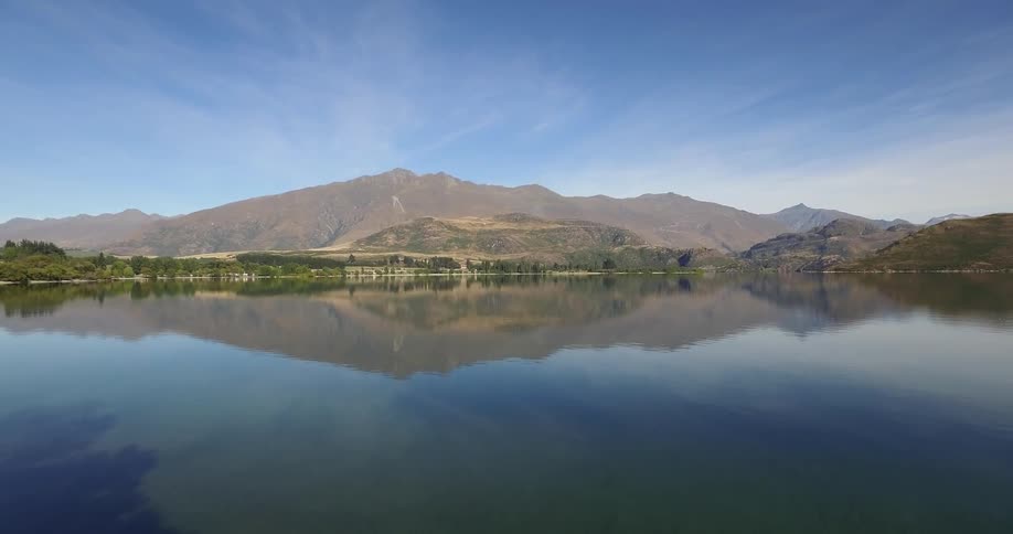A very still lake in front of a mountain range