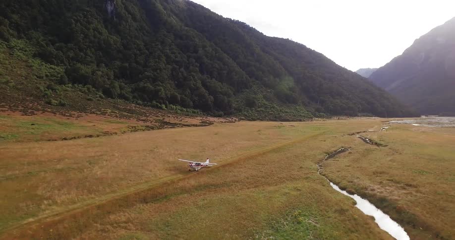 A small airplane traveling on a field in the wilderness
