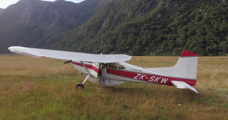 A man climbs into a white and red plane