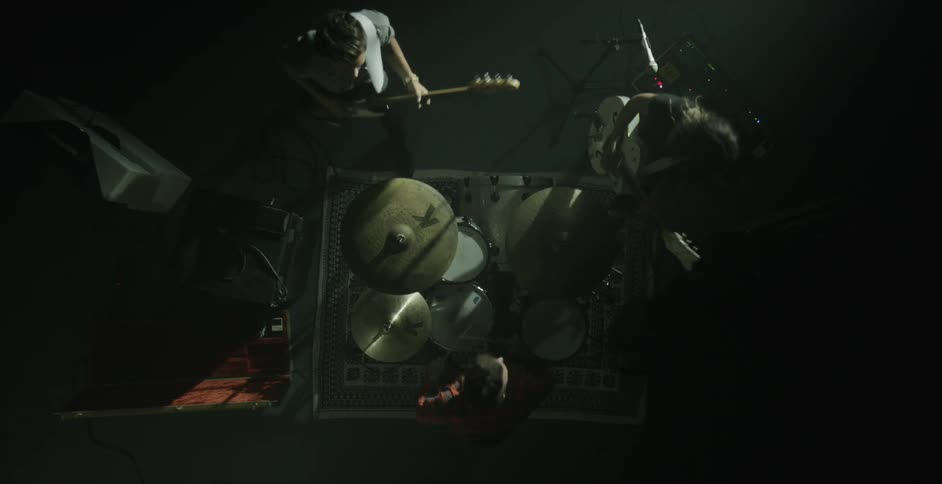 Three members of a band play on a soundstage