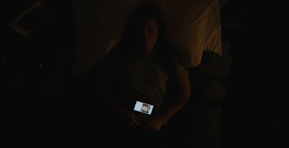 A woman with a phone on her stomach wakes up and gets out of bed