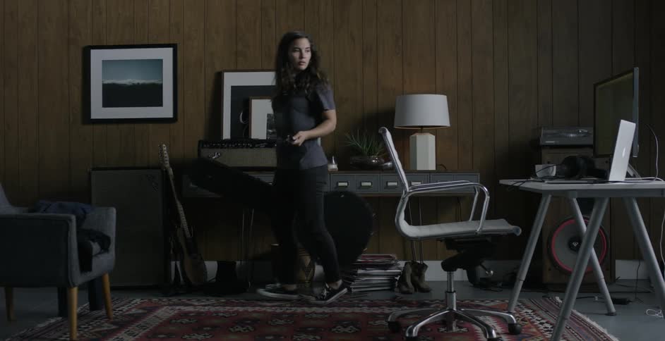 Woman walking into a recording studio picking up her guitar and walking away