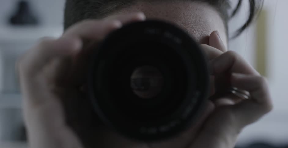 A person with dark hair adjusts a camera lens