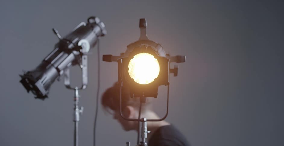 A man walks up to two stage lights as one of them turns on