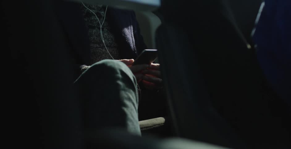A person in a gray sweater checks his phone in a vehicle
