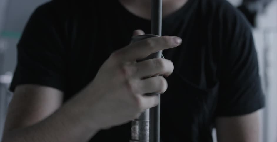 A man adjusts a metal pipe on a stand
