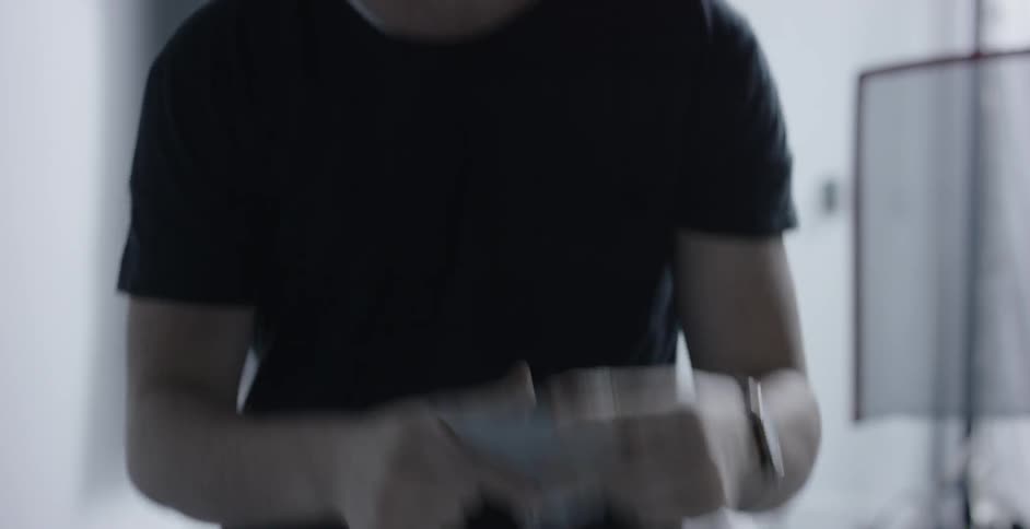 A man in a studio tears off a piece of black tape and marks a spot on the ground