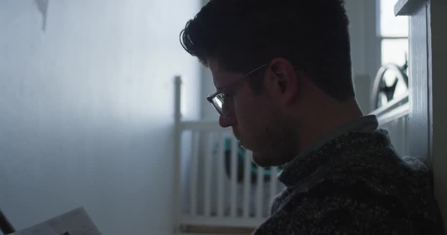 A man wearing reading glasses looks at a paper