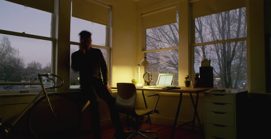 A man working in his home office, writing and on the phone