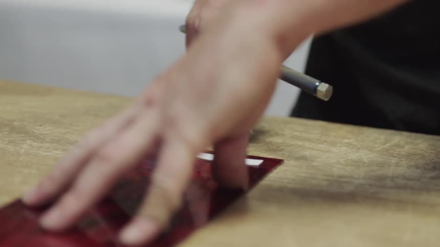 Hands holding down red glass to measure