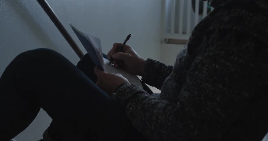 A person sitting in a stairwell writing notes