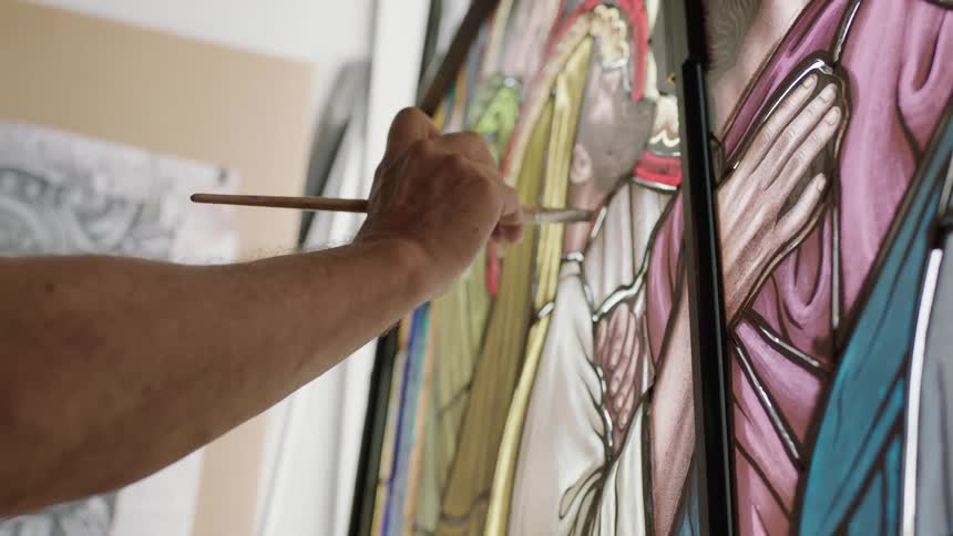 Hand holding a paint brush to stain glass