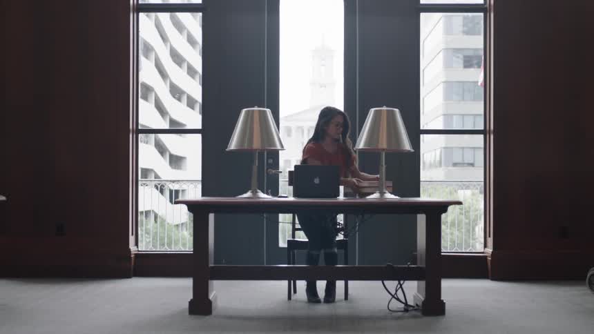 Woman sitting down at desk in front of three windows