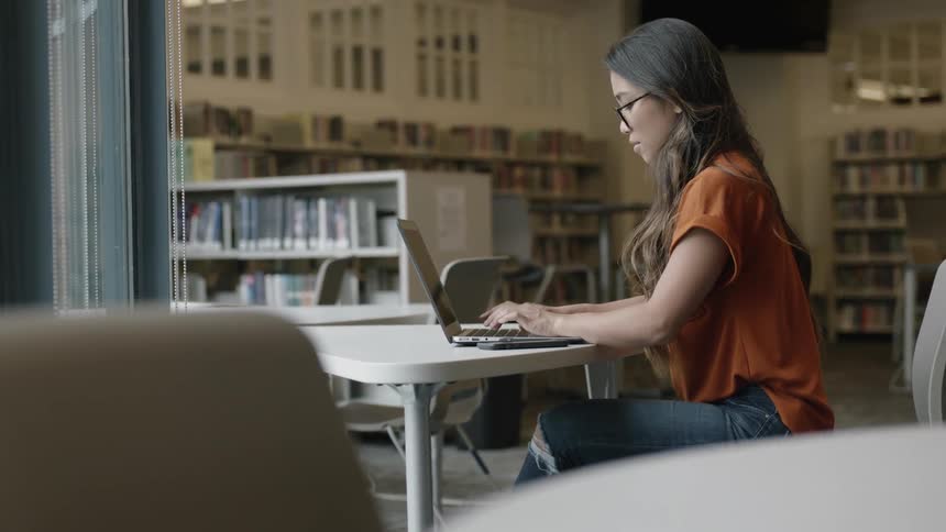 Young woman typing on laptop at table
