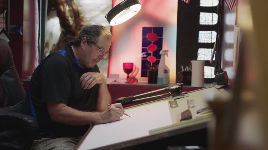 Man sitting at a desk in his office working on a picture