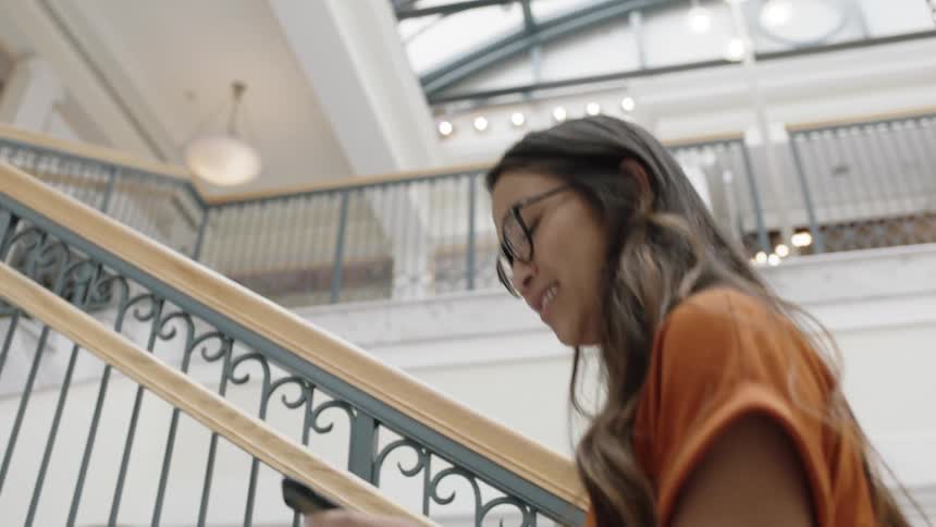 Asian woman walking up stairs waving at person
