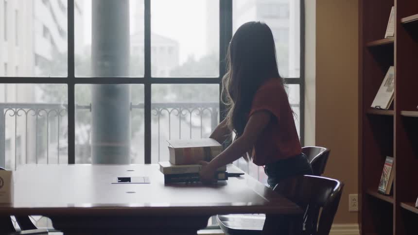 Young woman placing books on table