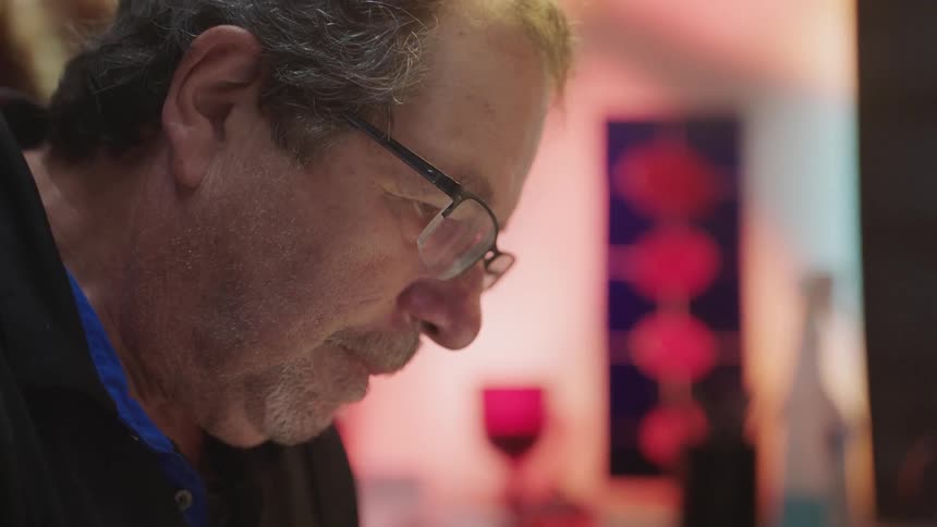 Man wearing glasses looks at paper on desk