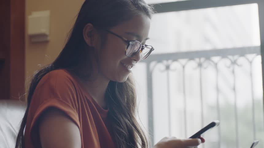 Girl with long hair looking at phone and laughing