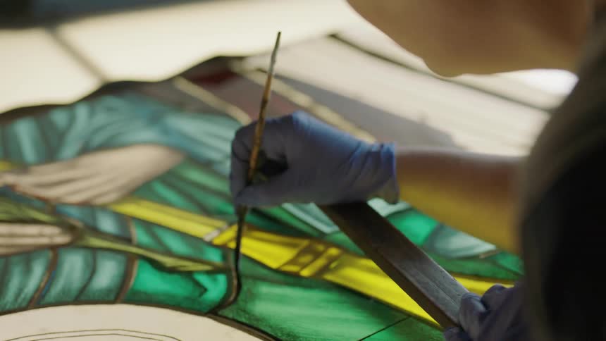 Artist leaning over to paint with fine point brush