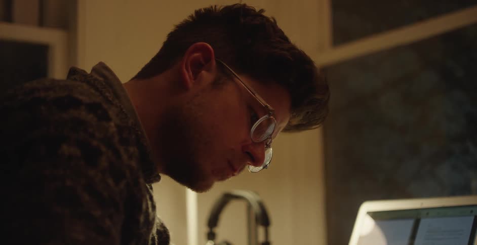 A man sitting at a desk looking down and writing