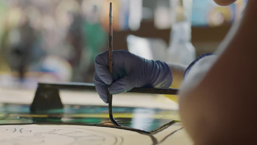 Hand with blue glove painting slowly