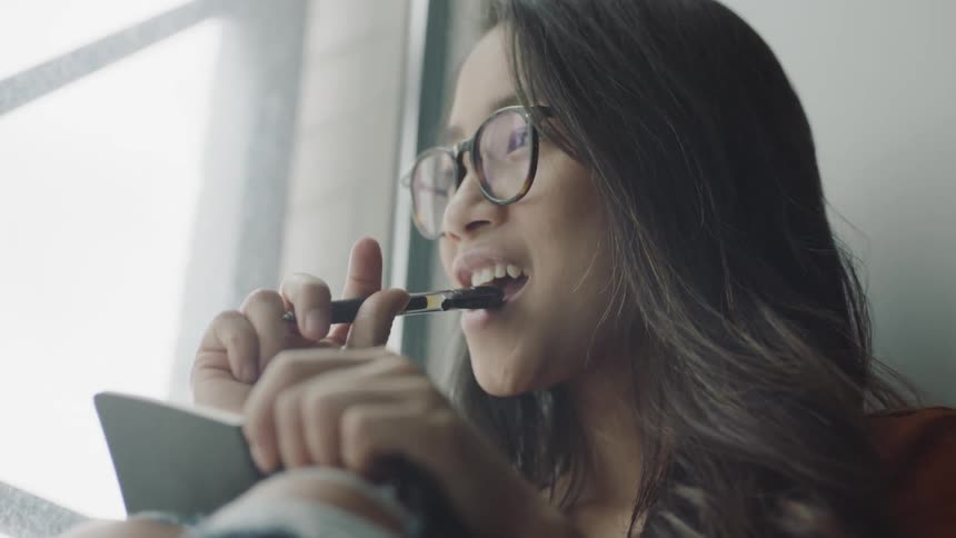 Young asian woman studying adding pen to mouth