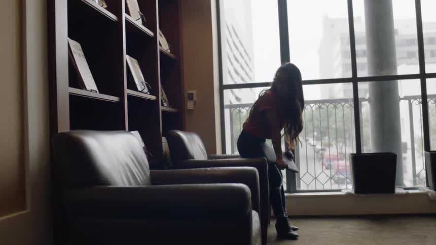 Girl walks in and sits in chair by window