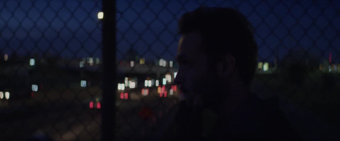 A man walking across a city bridge at night