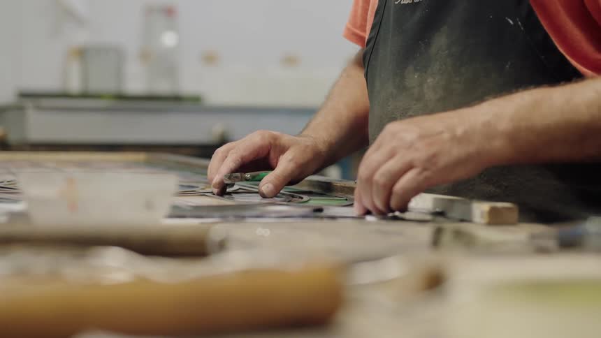 Hands cutting small pieces of glass