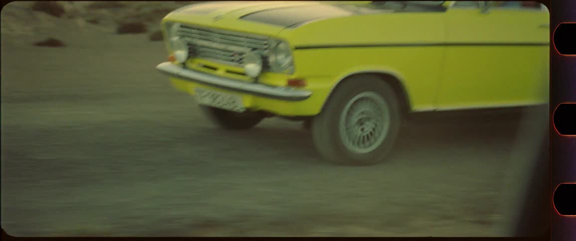 Closeup of a yellow car driving on a dusty road