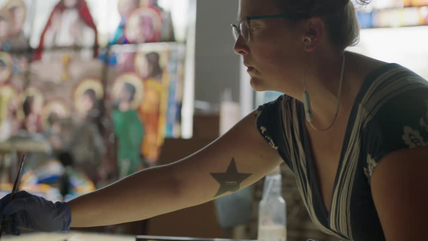 Female artist painting in front of window