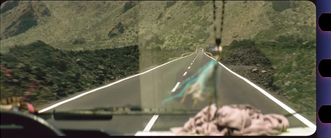 Dreamcatcher dangling in front of the windshield with a desert mountain scenery outside