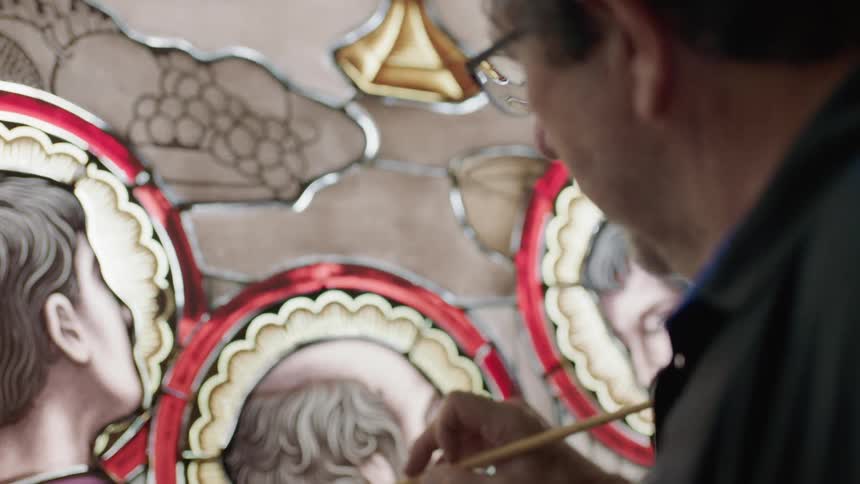Man with glasses works on stain glass image