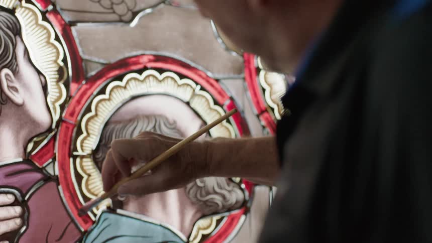 Older man painting on stain glass