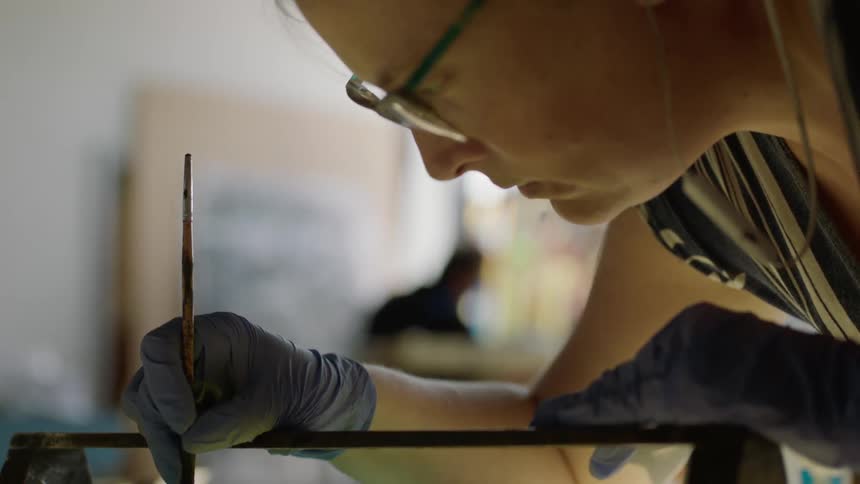 Focused painter leaning over artwork while listening to music