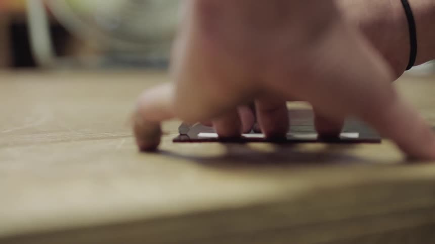 Hands holding and moving red object on table