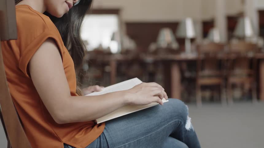 Woman wearing orange shirt looking down at book