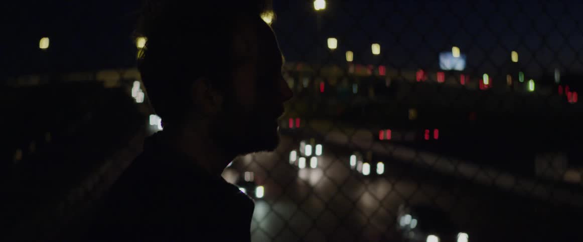 Man smoking and crossing a city bridge at night