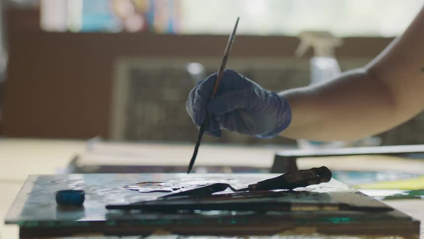 Hand holding paint bush and making small strokes
