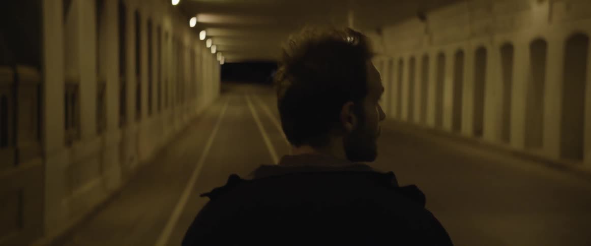 Man walking through a city tunnel at night