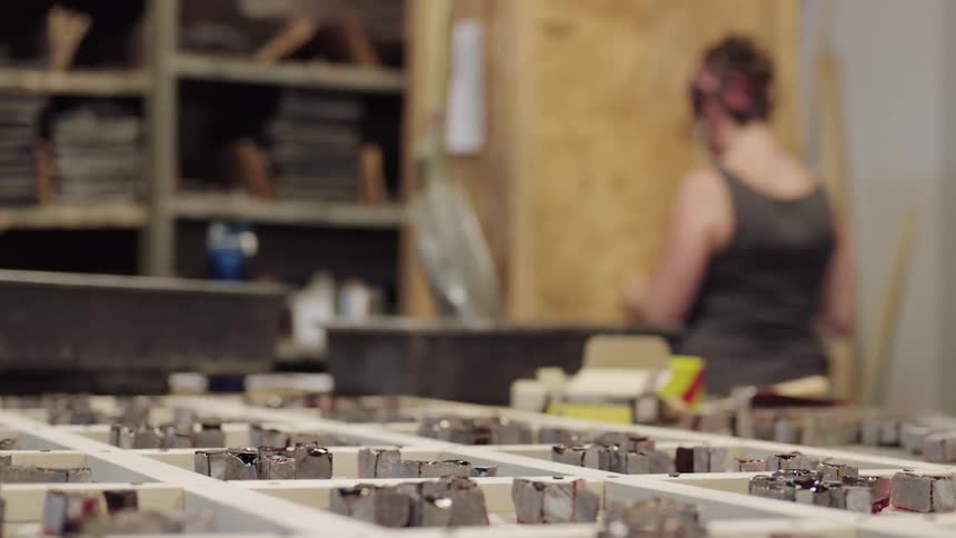 Focus on clay cubes and woman with tool