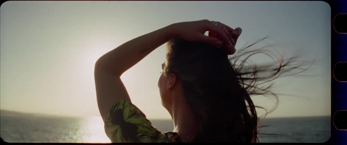 Woman enjoys the sunset and the wind next to the ocean