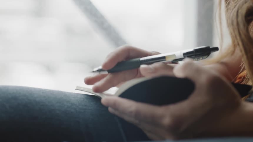 Writing in notebook in front of window