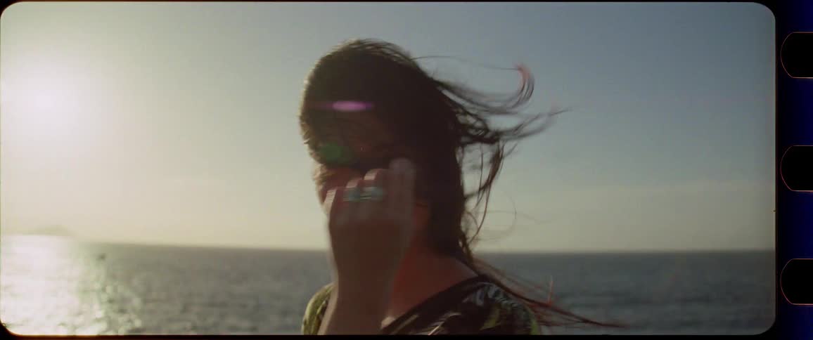 Woman enjoys the sunset next to the ocean with wind in her hair